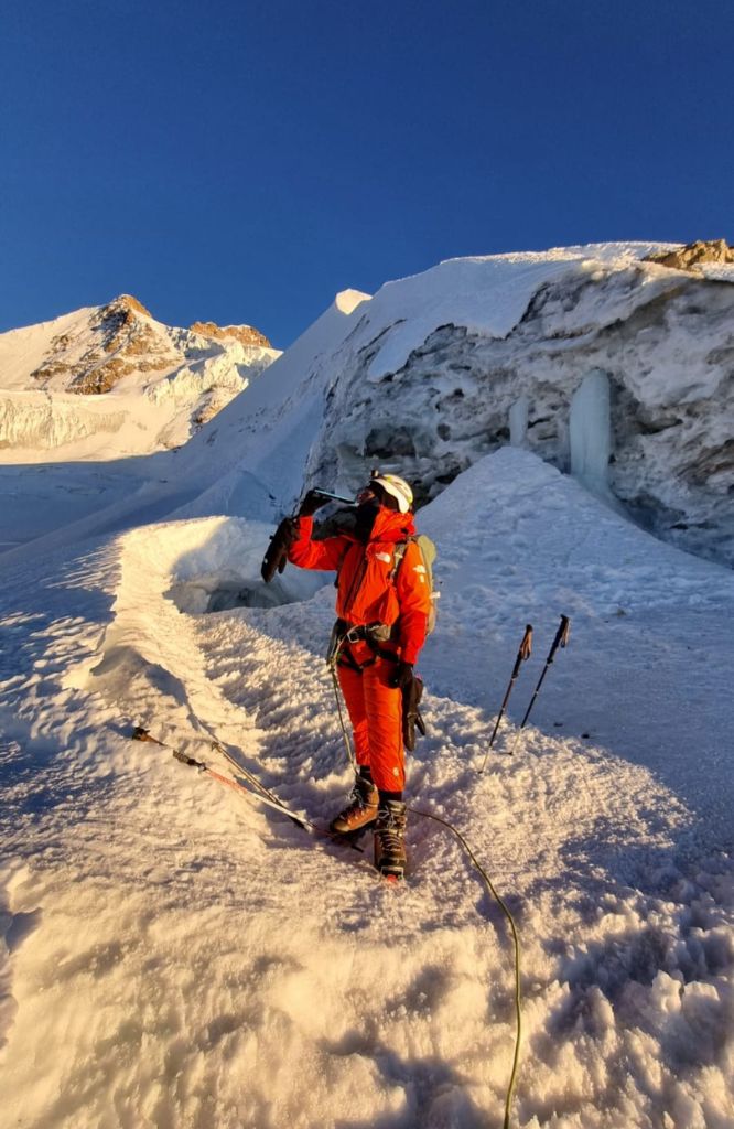Mulher vestida e laranja caminhando em montanha nevada
