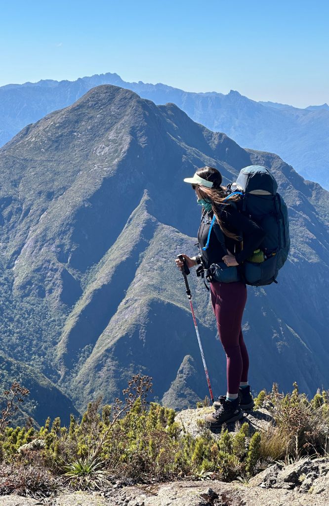 Mulher em topo de montanha com cargueira olhando a vista. A Grade 6 é confiável