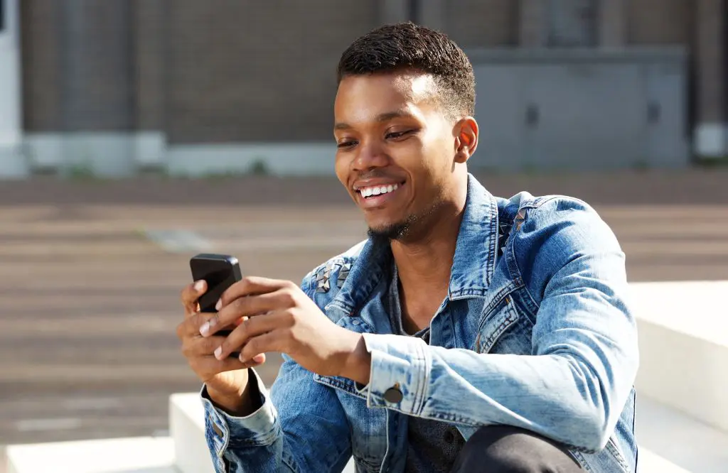 homem com jaqueta jeans usa seu celular com o cupom holafly