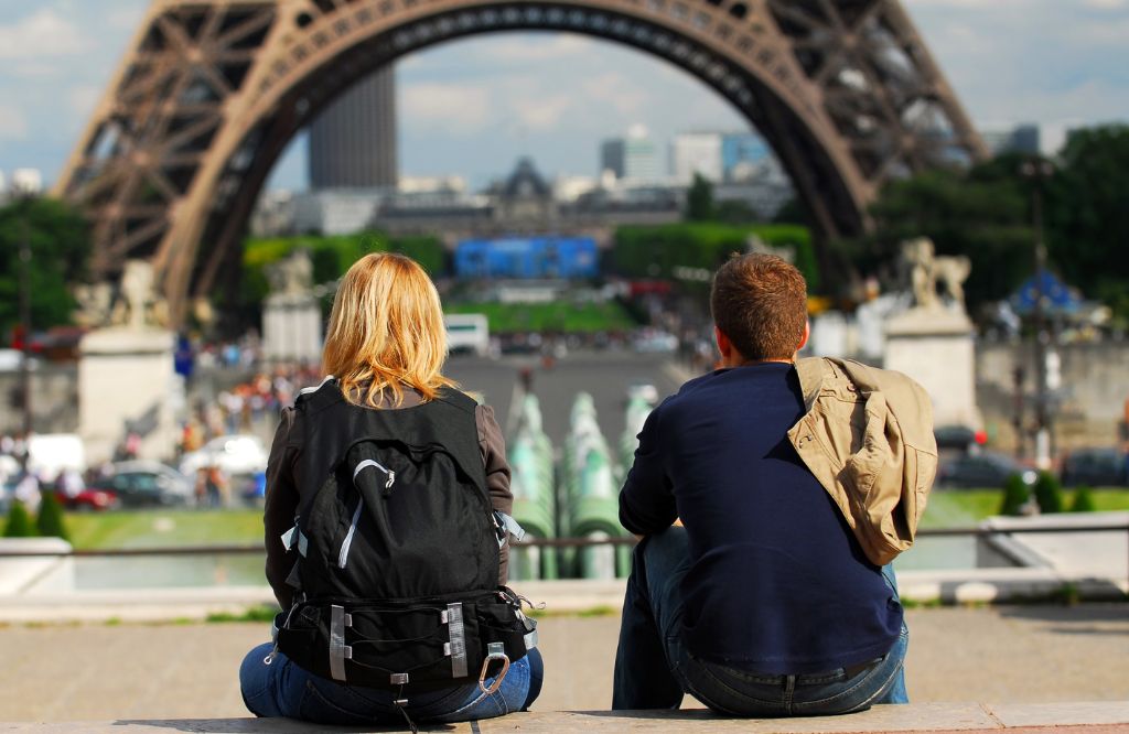 casal sentado em frente à Torre Eiffel